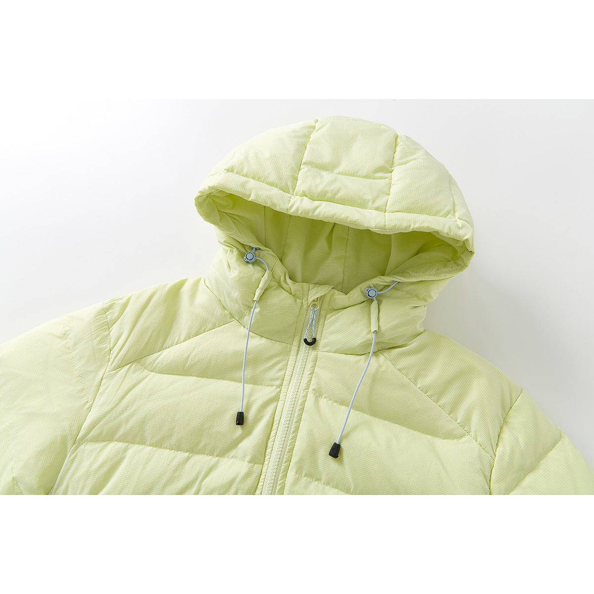 Close-up of a pale yellow-green quilted jacket hood, drawcords, and front zipper.