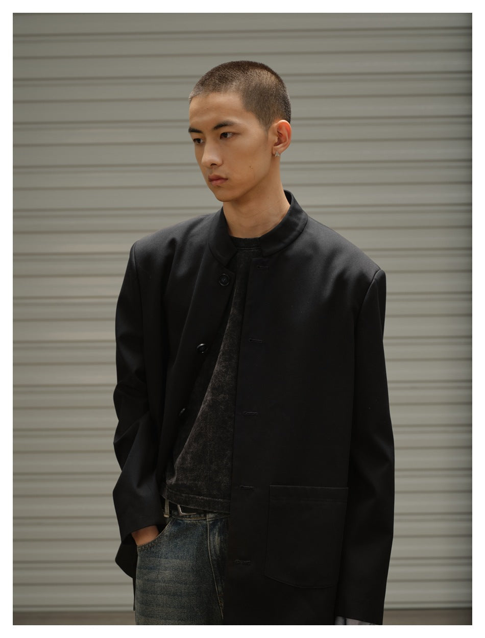 Close-up of model in black stand-collar button jacket with patch pocket, hand in pocket