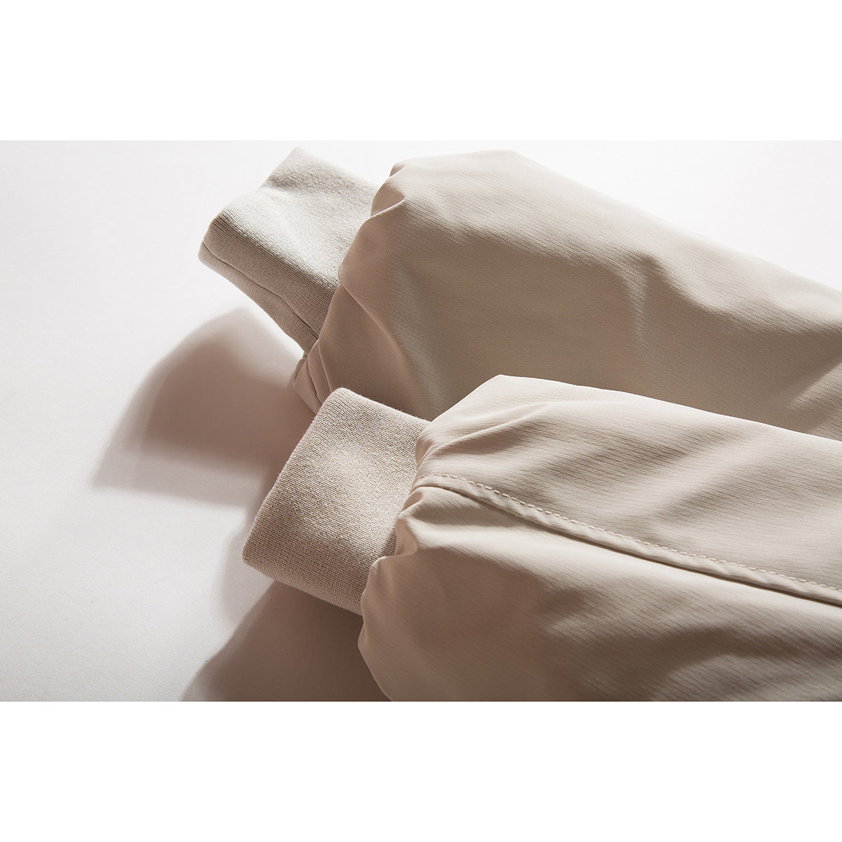 Close-up of a beige jacket's folded sleeves and ribbed cuffs.