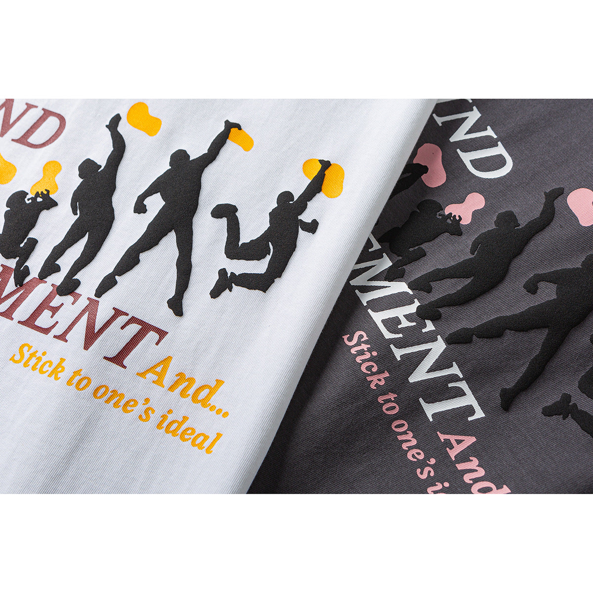 Close-up of white and charcoal T-shirts with printed silhouettes and English lettering in contrasting colors.
