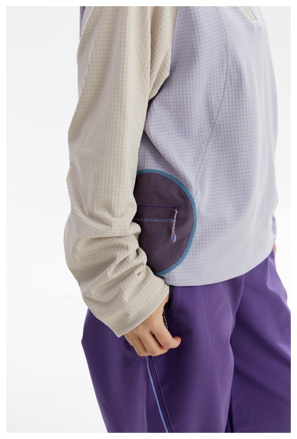 Close-up of the pullover's curved purple zip pocket with teal edging and the purple pants.