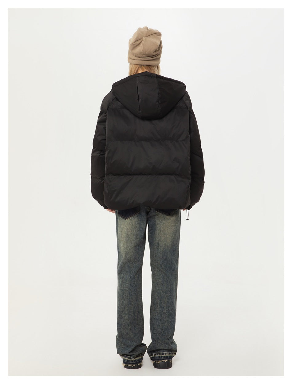Back view of a person wearing a black hooded puffer jacket, blue jeans, and a beige beanie.