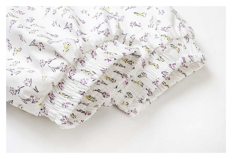 Close-up of the gathered elastic hem and cuff area of a white garment with pink and yellow floral print.