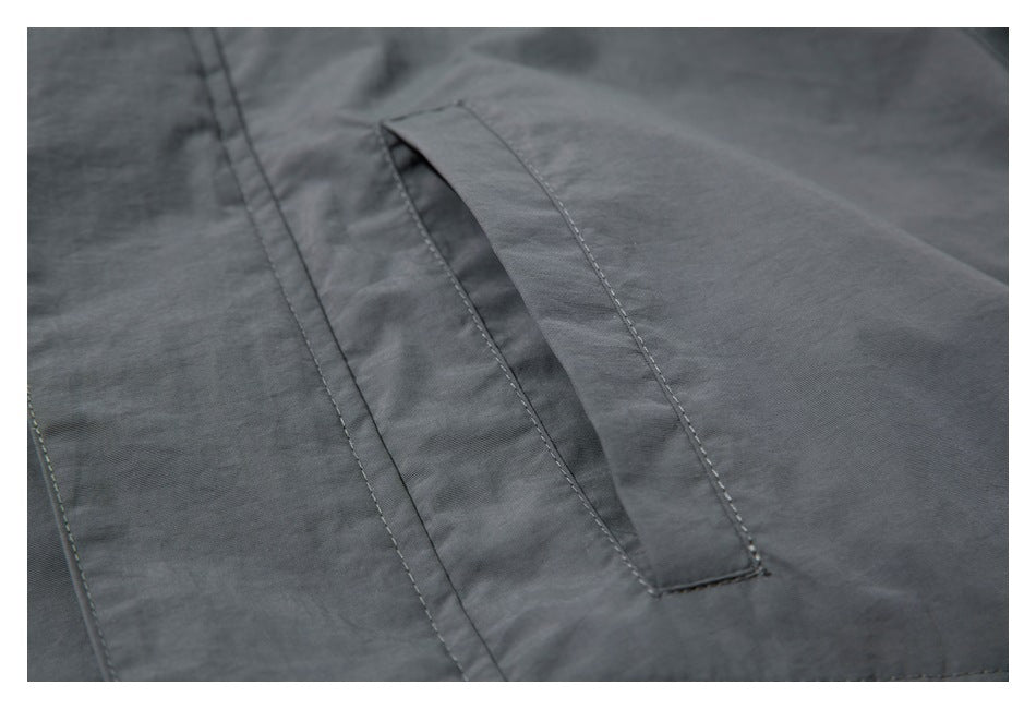 Close-up of a slanted welt pocket on a dark gray jacket.