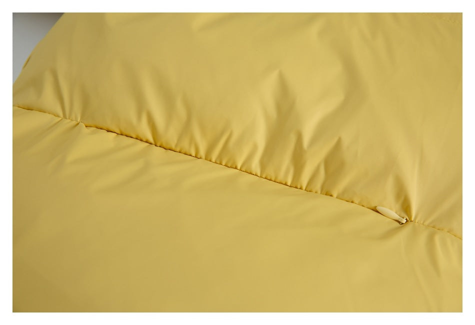 Close-up of a yellow jacket seam and pocket opening with a small zipper pull.