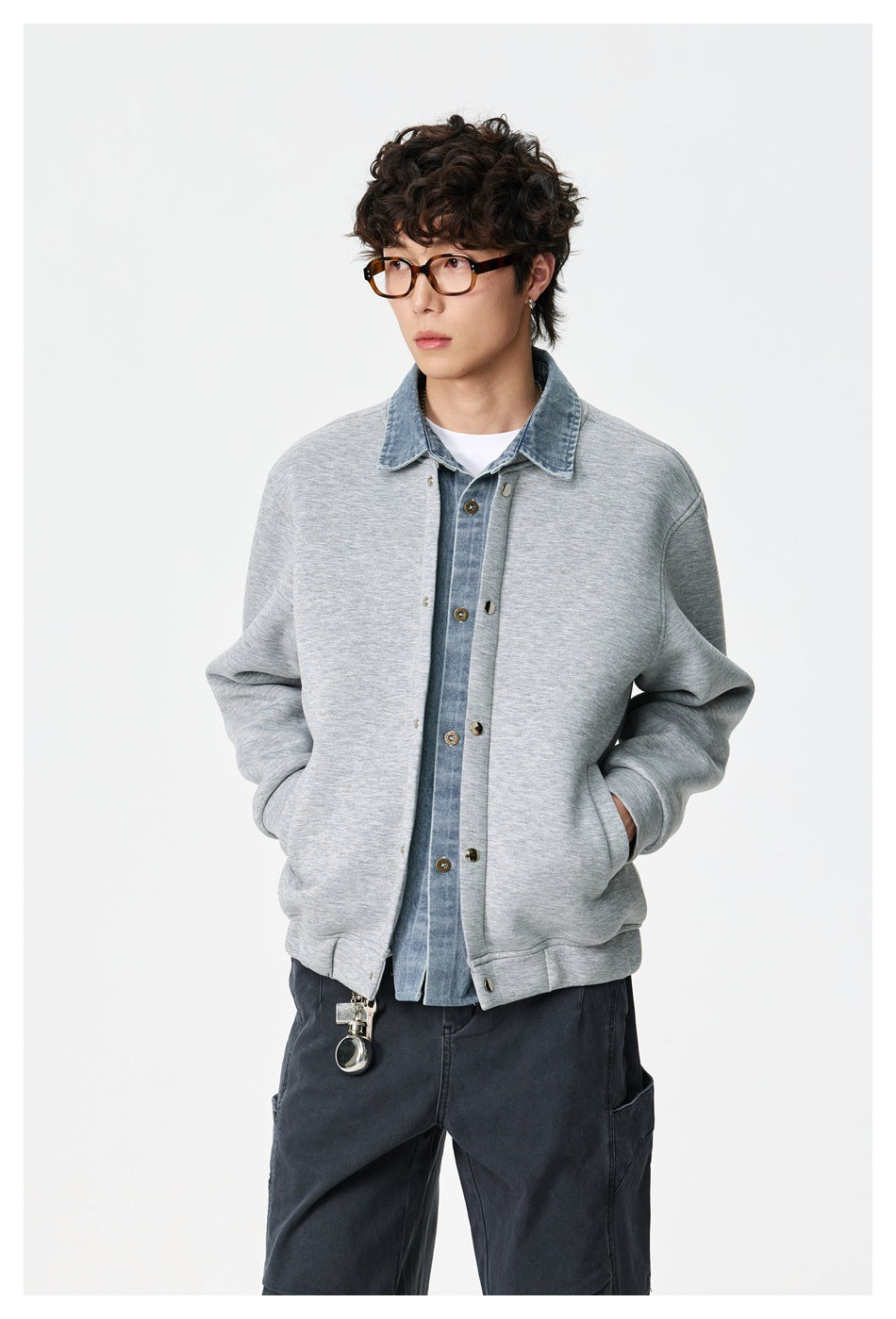 Closer front view of a model wearing a light gray snap-front jacket with a blue denim collar and white shirt.
