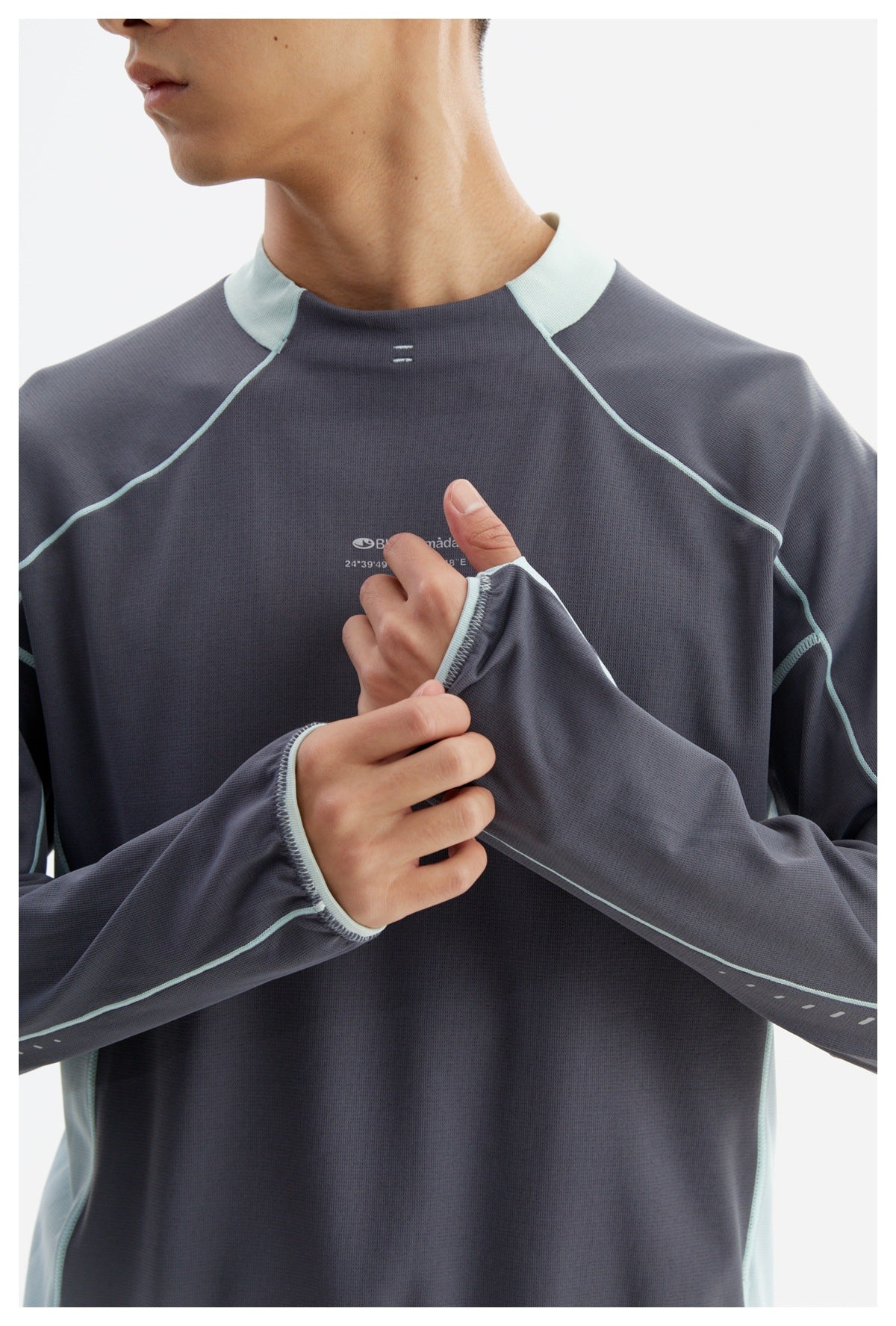 Close view of a model wearing a charcoal long-sleeve top with pale aqua trim and panels, showing the cuff and chest print.