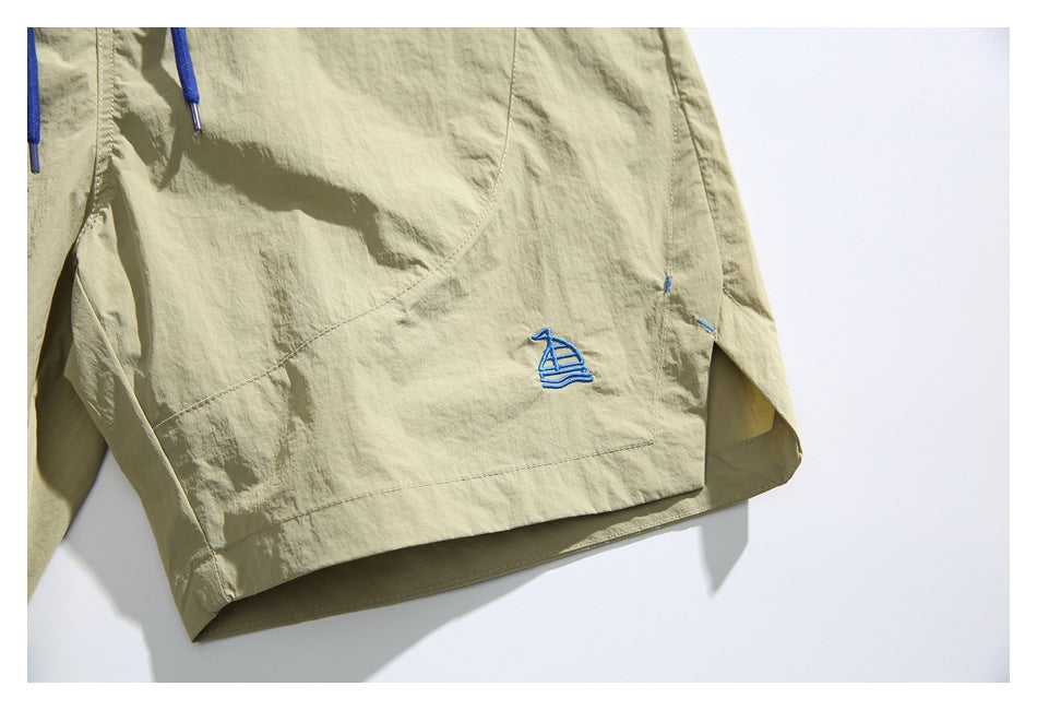 Close-up of a leg hem with blue sailboat embroidery and a glimpse of the blue drawstring.