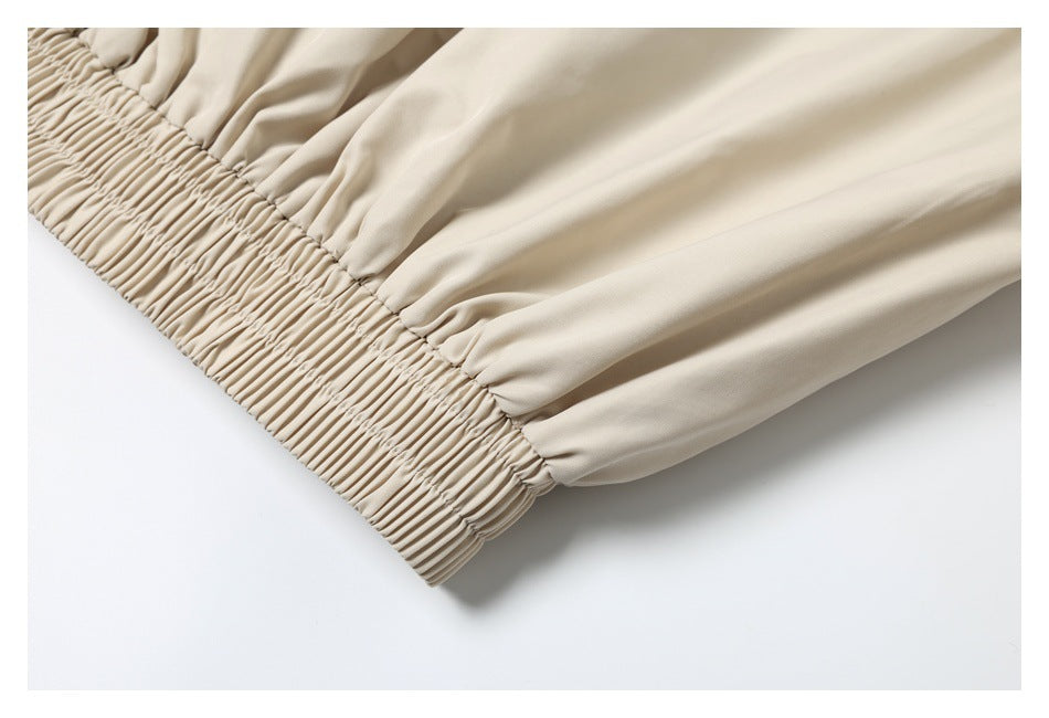 Close-up of a beige garment with a wide, densely elasticized gathered edge.