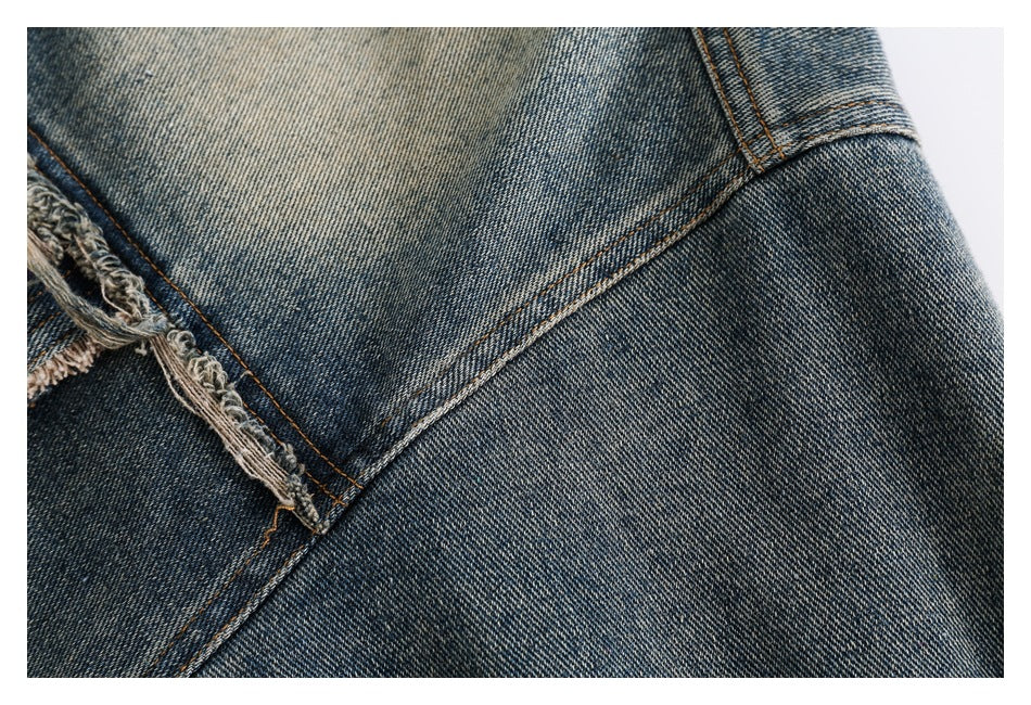 Close-up of the jacket's faded blue denim and diagonal seam stitching beside a frayed edge.
