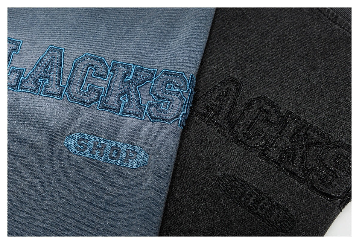 Close-up of blue-gray and black shirts with raised collegiate-style lettering embroidery.