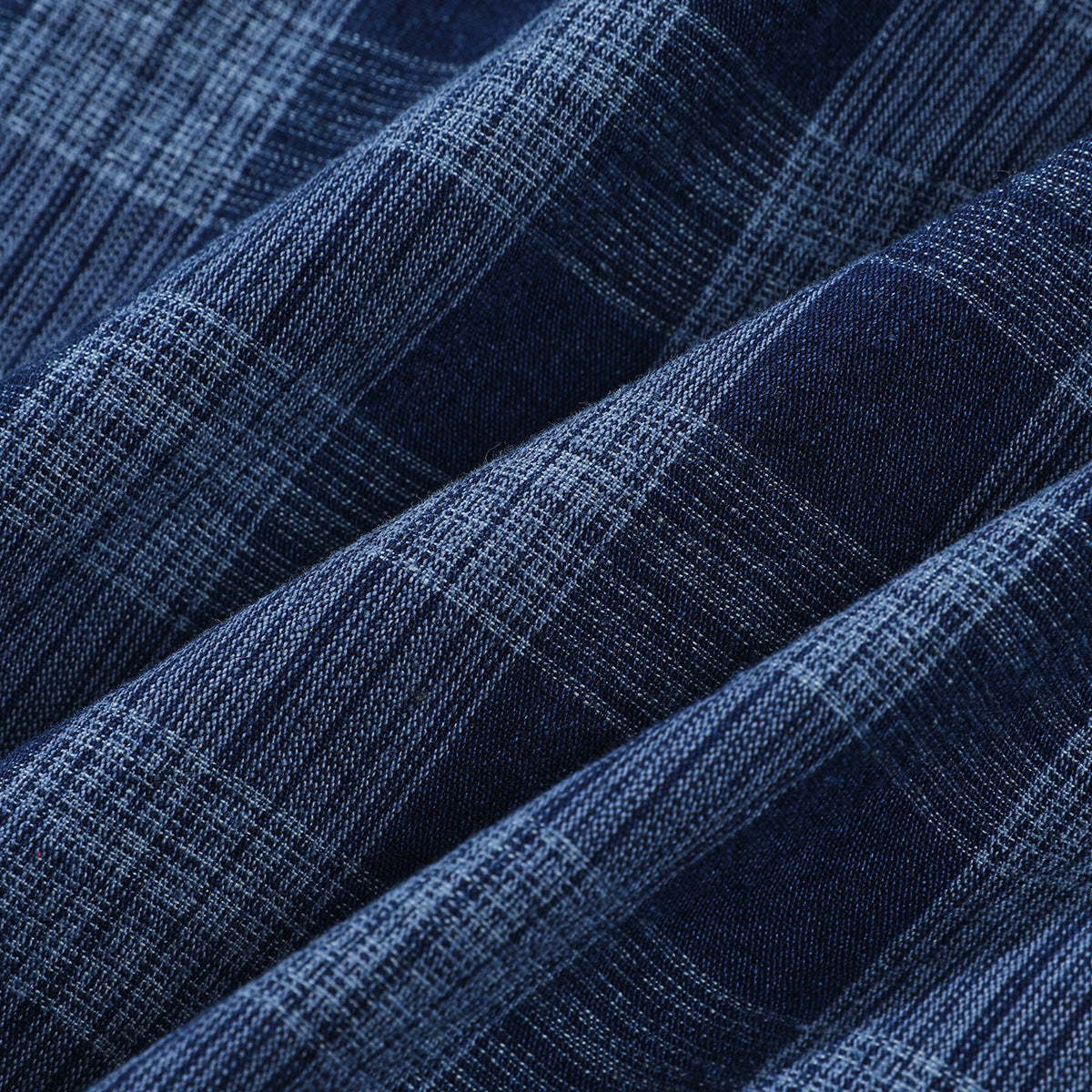 Macro view of dark blue plaid fabric arranged in soft folds.