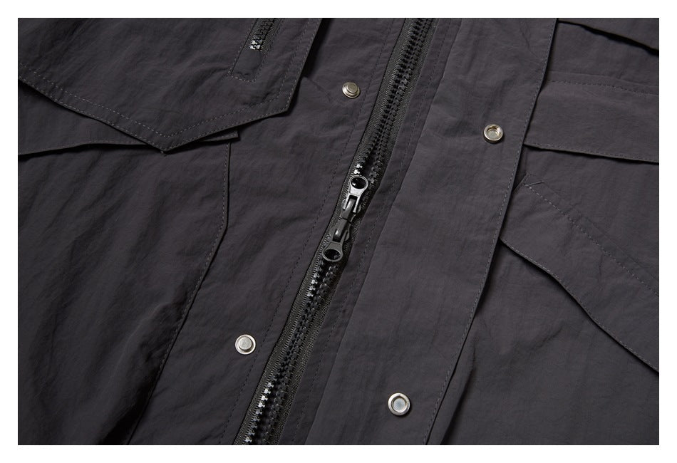 Close-up of the garment's dark front zipper, snap fasteners, and flap pockets.