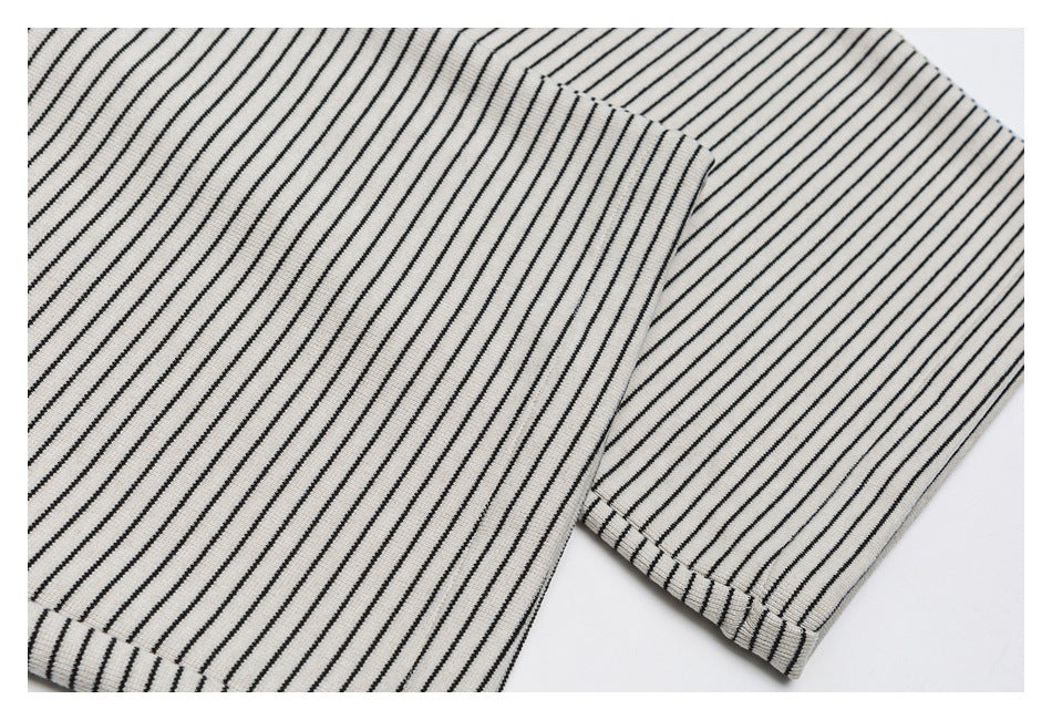 Close-up of the striped pants legs and stitched hems, with narrow black stripes on cream fabric.