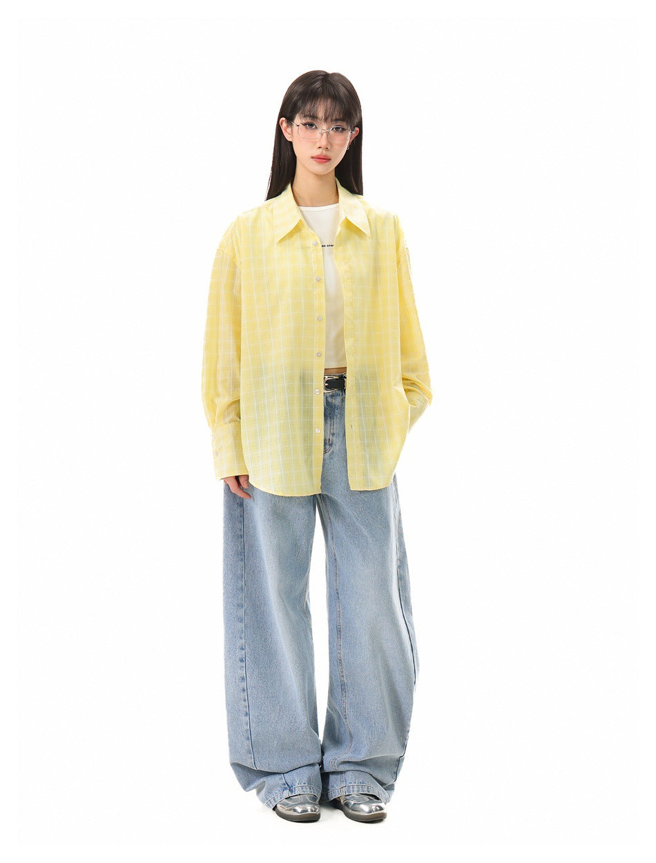Model wearing yellow plaid shirt open over a white top with wide-leg light blue jeans, full-length view