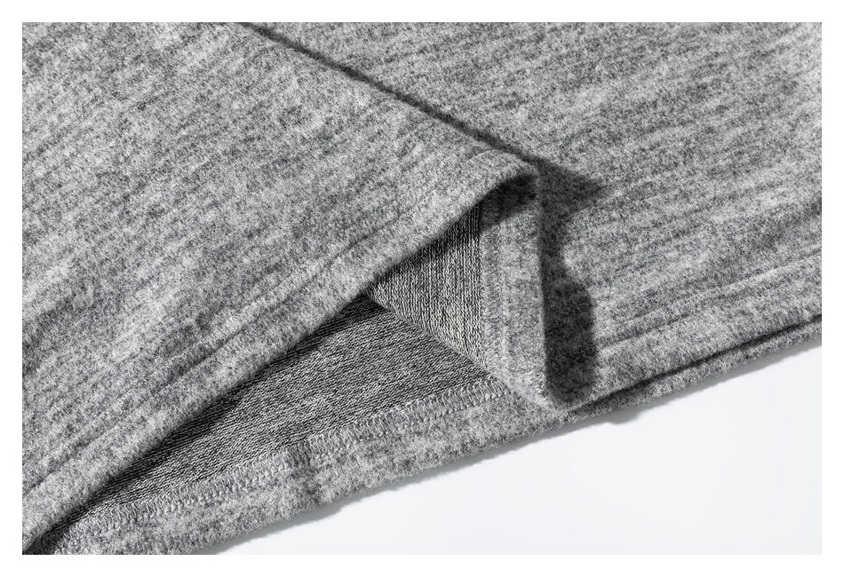 Close-up of the gray marled top's folded hem and interior overlocked seam.