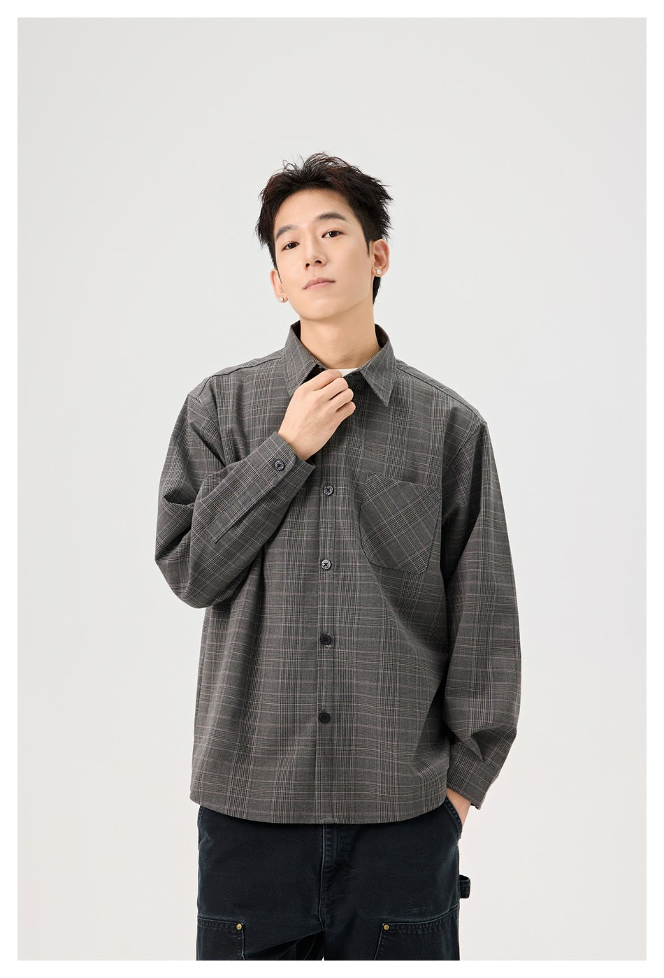 Model wearing a gray plaid button-up shirt with a chest pocket, touching the collar.