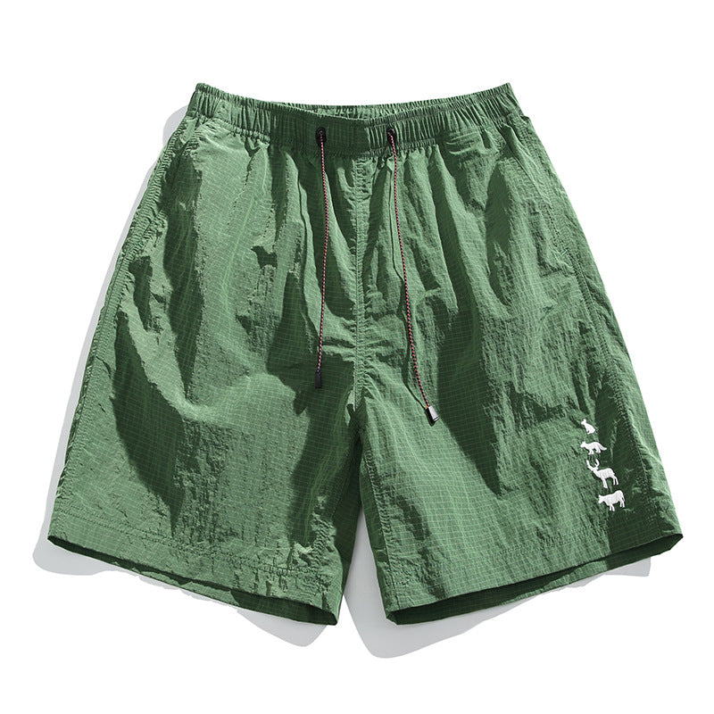 Green textured drawstring shorts with subtle grid pattern and white animal embroidery near the hem, flat lay