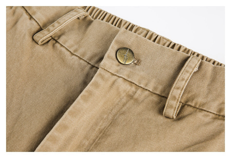 Close-up of tan pants with an elastic waistband, belt loops, and a metal button.