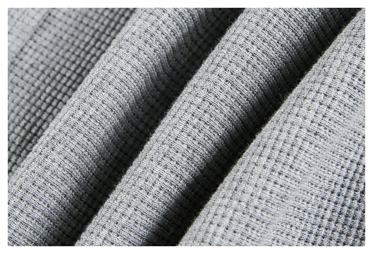 Macro view of light gray fabric showing its raised, grid-like knit texture.