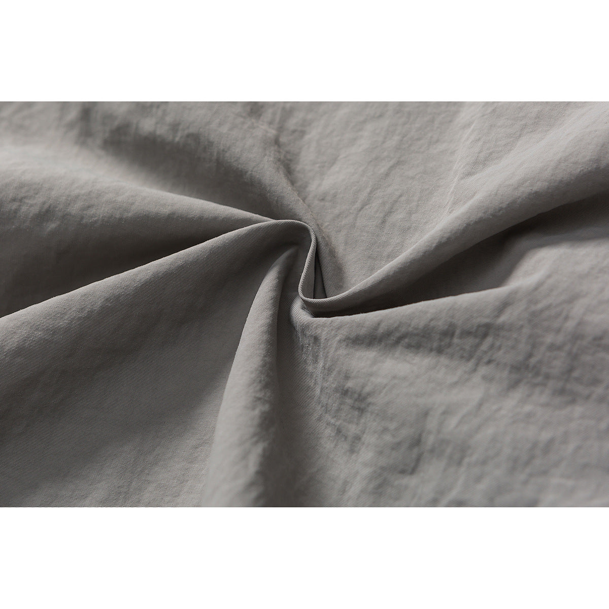 Extreme close-up of gray shorts fabric gathered into soft folds, showing its fine surface texture.
