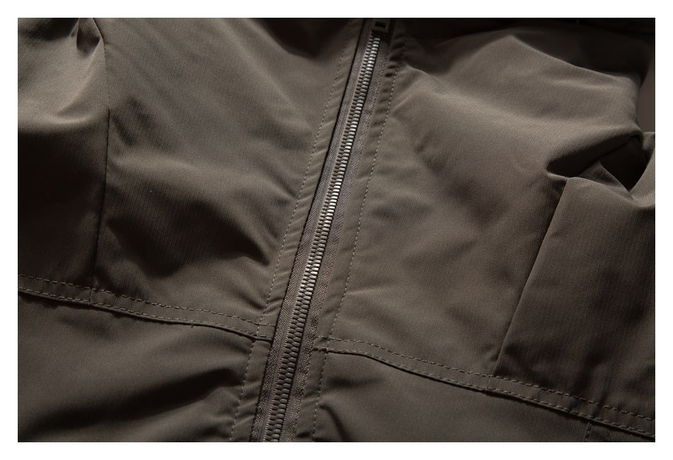 Close-up of a dark taupe jacket with a central zipper and stitched panel seams.