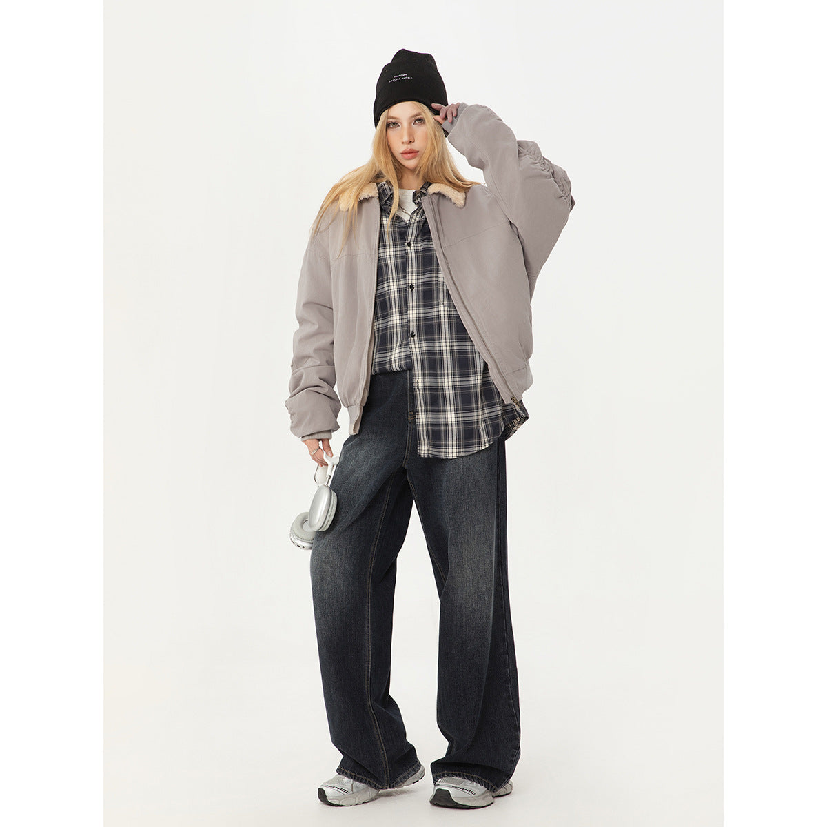Model wearing a light gray shearling-collar bomber jacket, plaid shirt, and wide-leg dark jeans.