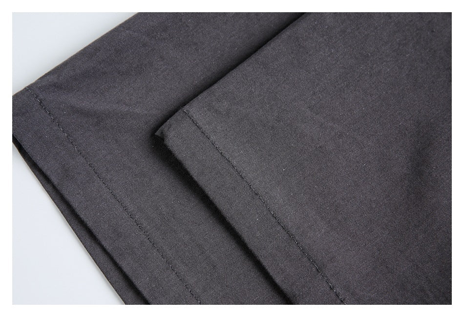 Close-up of overlapping charcoal garment edges with stitched hems.