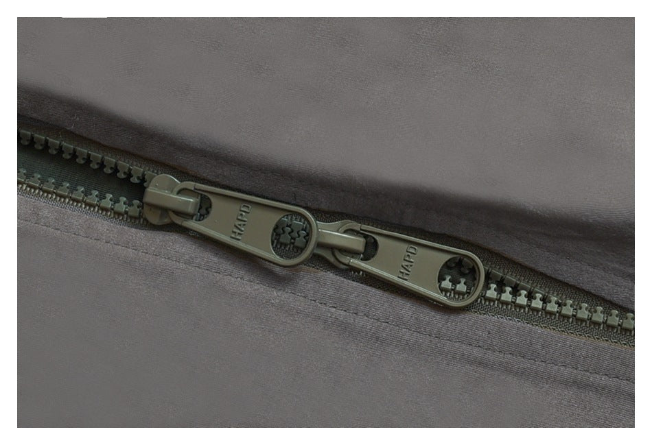 Close-up of two dark olive zipper pulls on gray jacket fabric.