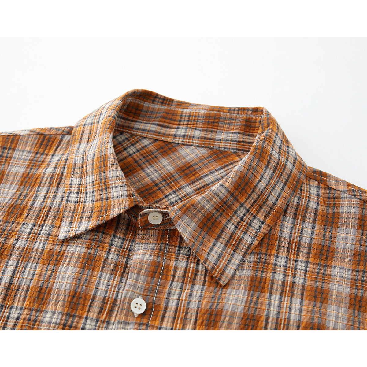 Close-up of an orange, gray, and cream plaid shirt collar and button placket.