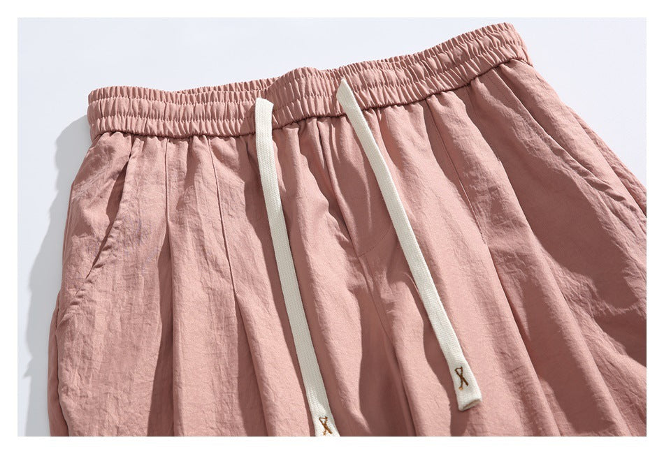 Close-up of the pants’ gathered elastic waistband, cream drawstrings, and front pleats.