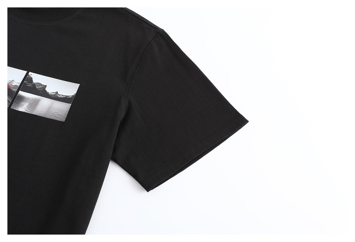 Close-up of a black T-shirt showing part of its landscape graphic, crew neck, and short sleeve.