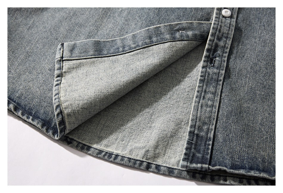 Close-up of the lower hem of a dark gray washed denim shirt, folded back to show its lighter interior.