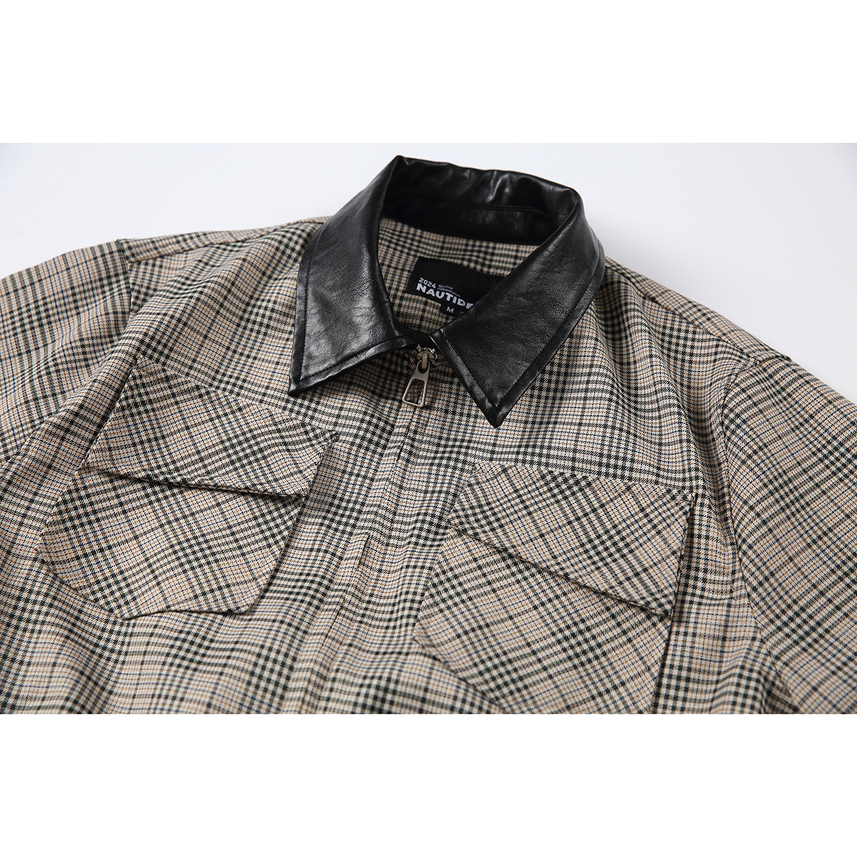 Close-up of a beige, black and brown plaid zip-front shirt with two flap chest pockets and a contrasting black collar.