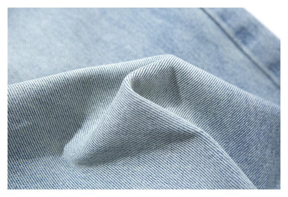 Macro view of folded light blue denim showing its diagonal weave and washed surface.