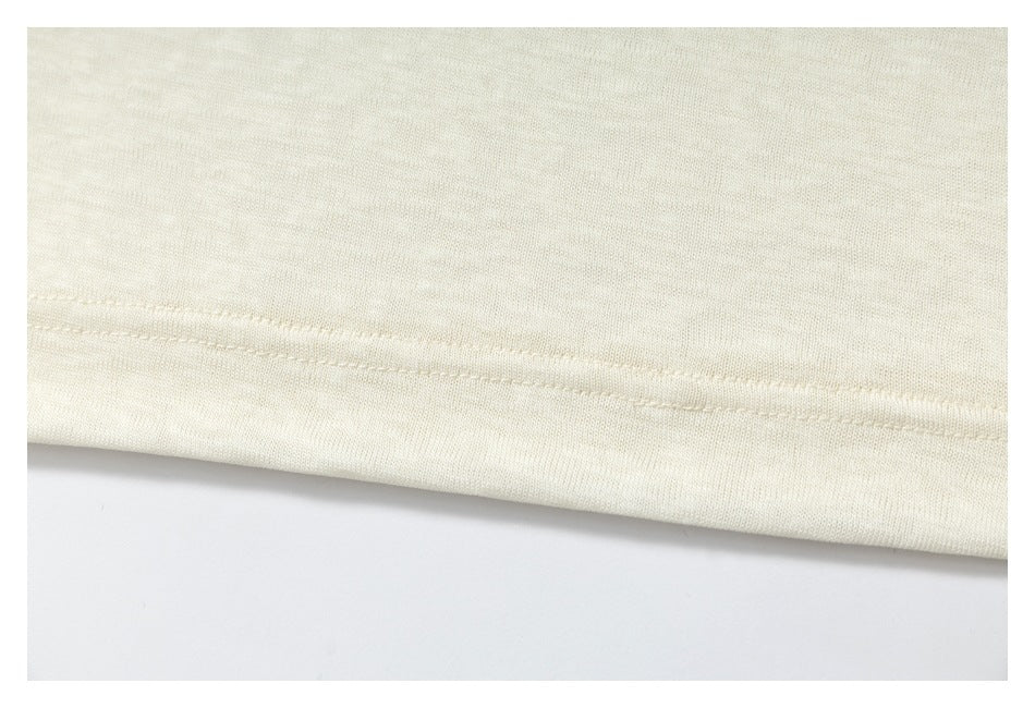 Close-up of an ivory garment's double-stitched hem against a white background.