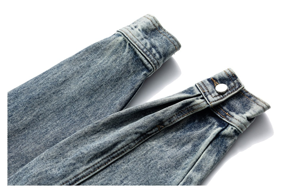 Close-up of a blue denim jacket sleeve cuff with a metal snap closure.