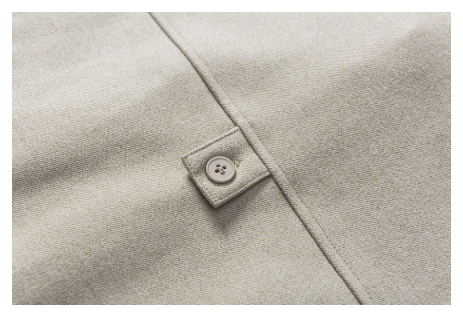 Close-up of a beige woven garment with a small four-hole button on a stitched tab.