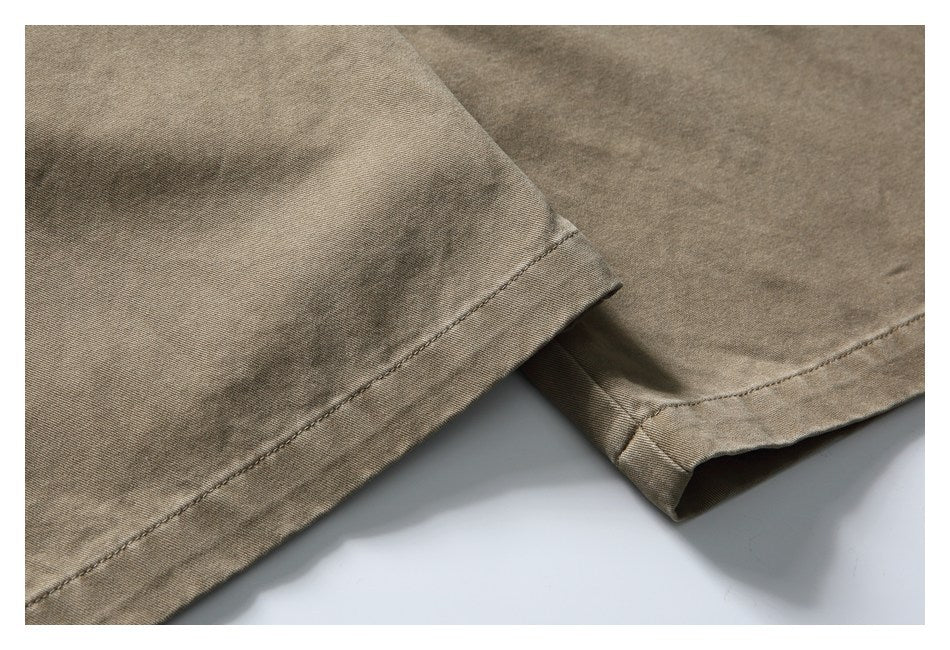 Close-up of taupe trouser legs showing the stitched hems.