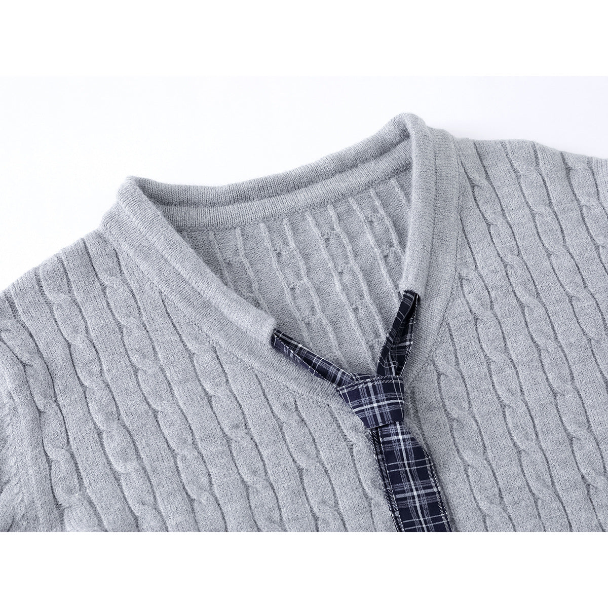 Close-up of a light gray cable-knit sweater neckline with a dark navy plaid tie detail.