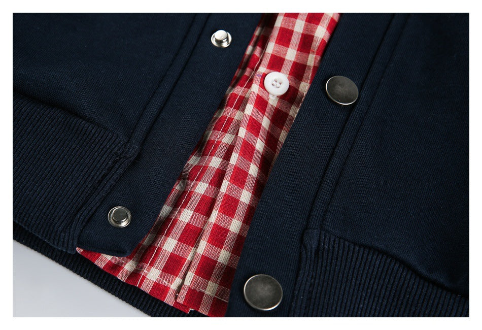 Close-up of the checked placket, snap fasteners, and ribbed hem on a navy garment.