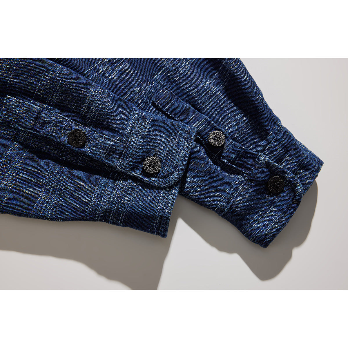 Close-up of the blue plaid shirt's buttoned sleeve cuffs and adjustable tabs.