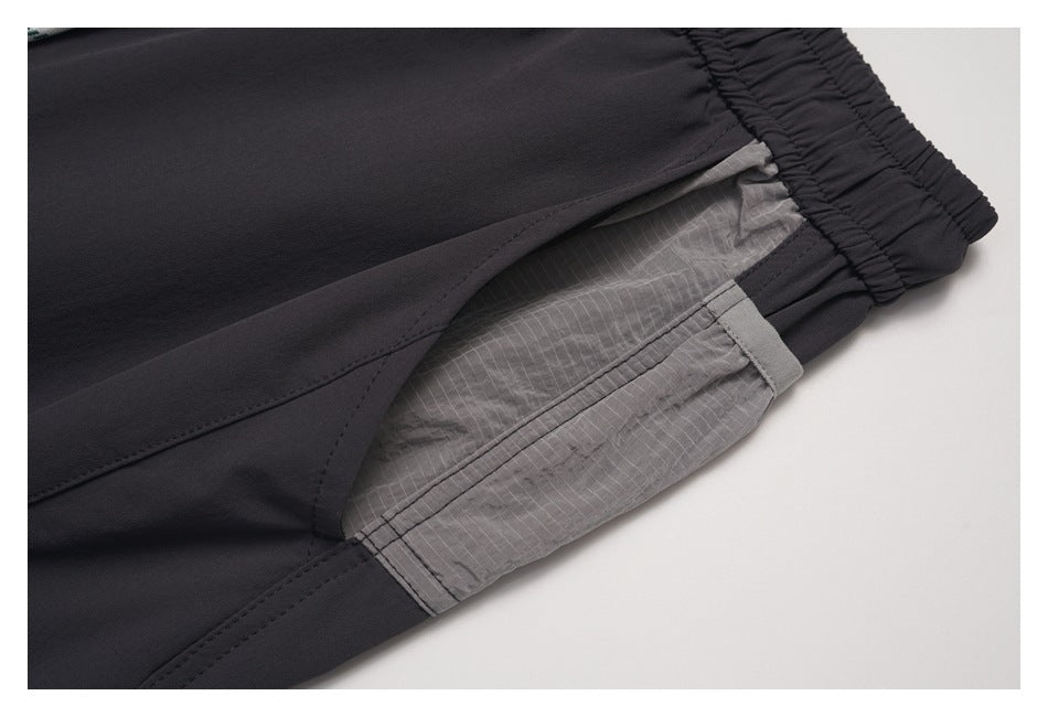 Close-up of a gray side pocket panel and stitching on charcoal pants.