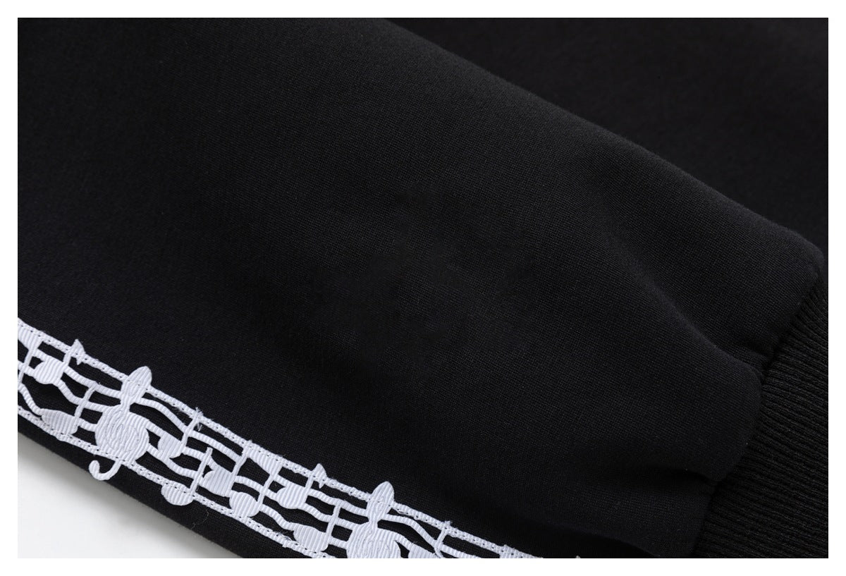 Close-up of a white musical-note stripe on black fabric beside a ribbed cuff.