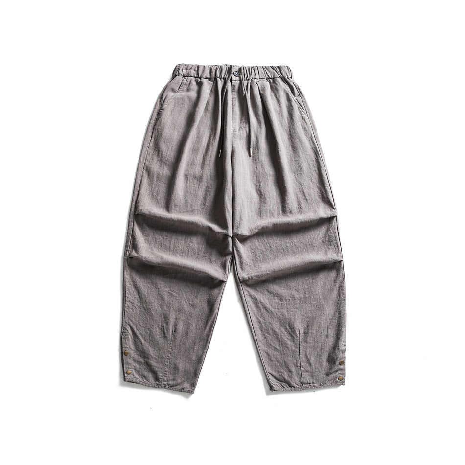 Gray wide-leg textured pants flat lay with elastic drawstring waist, side pockets and hem snap buttons