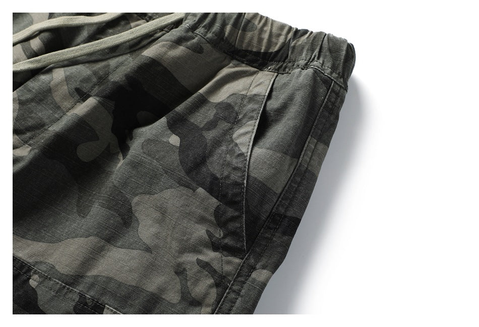 Close-up of the camouflage pants’ gathered elastic waistband, side seam, and curved pocket opening.