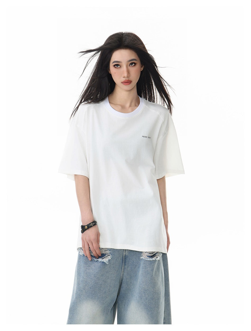 Model wearing white oversized short-sleeve crew-neck T-shirt with wide light-wash distressed jeans, front view