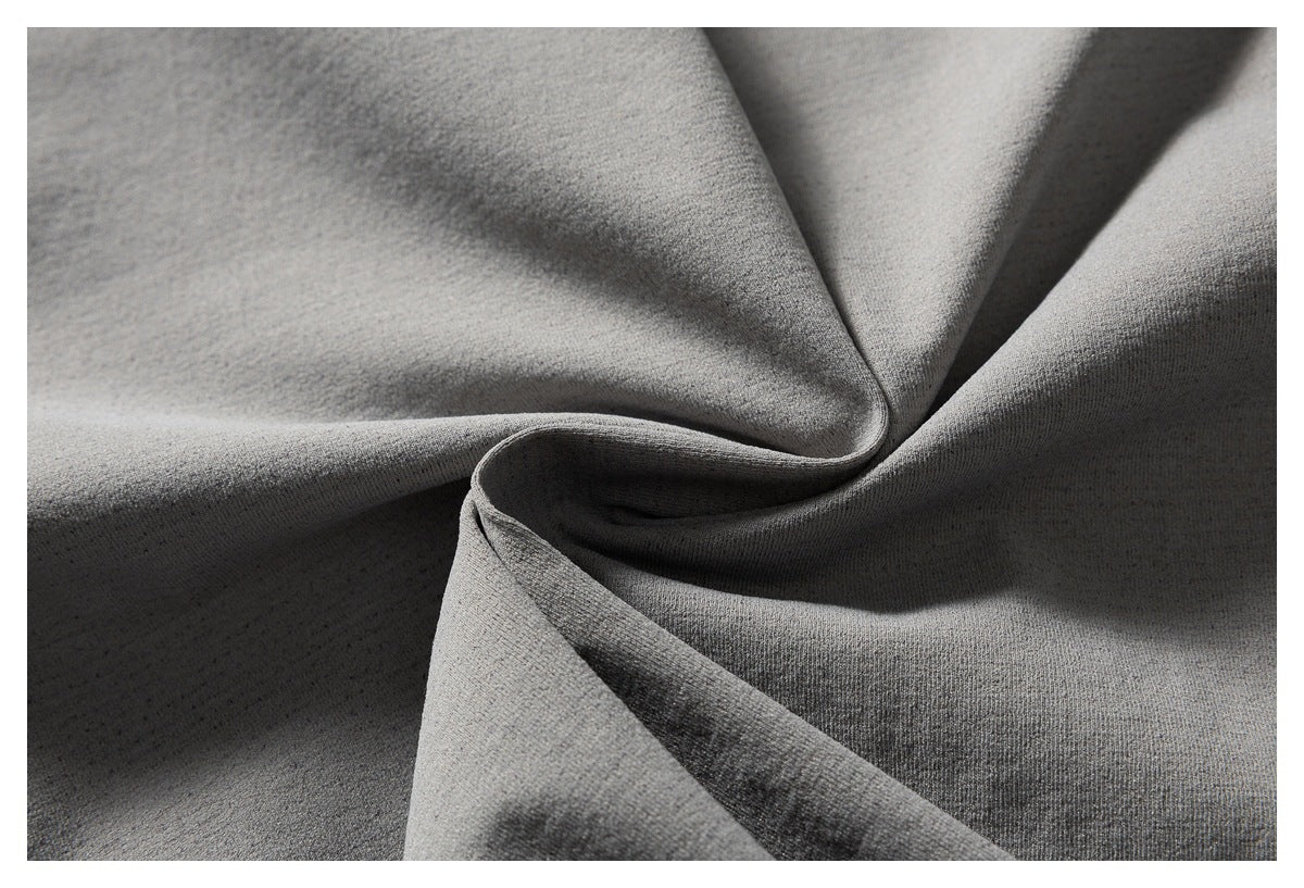 Close-up of gray fabric draped into folds, showing its fine surface texture.