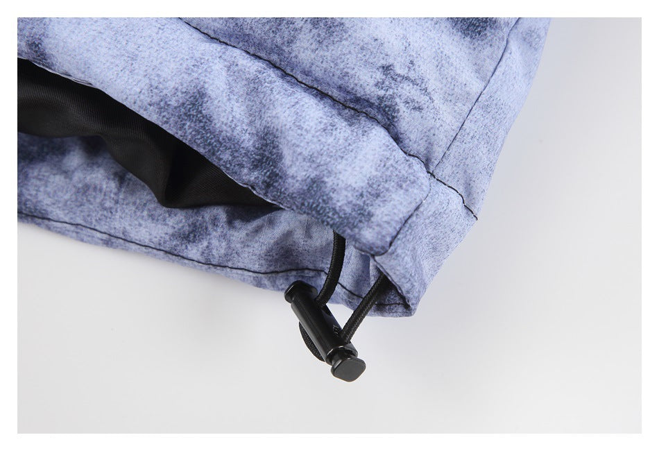 Close-up of the jacket hem with a black drawcord and toggle against mottled blue-gray fabric.