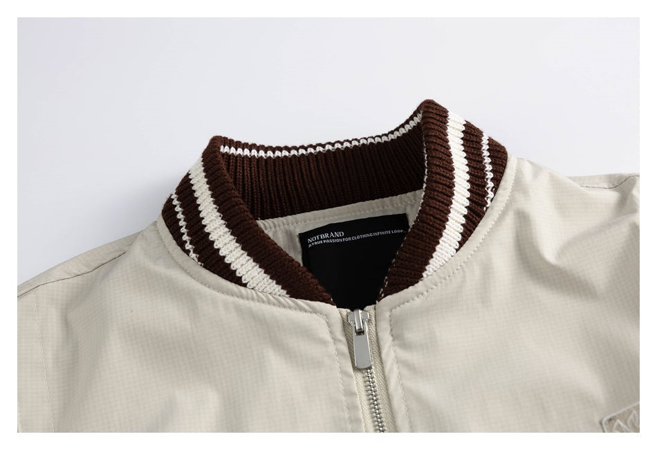 Close-up of a light beige jacket's zip front and dark brown ribbed collar with cream stripes.